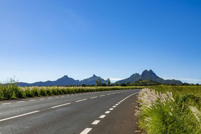 Road by mountain against blue sky