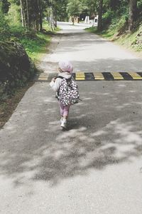 Rear view of girl walking on road
