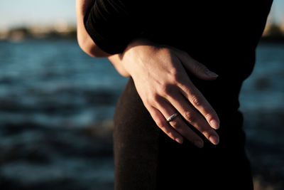 Midsection of woman wearing ring while standing at beach