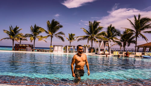 Young man in swimming pool against sky