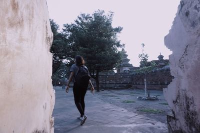 Rear view of man walking on footpath in city