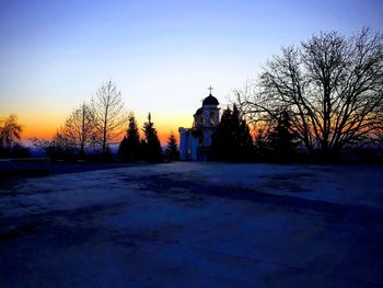 Bare trees and buildings against sky during winter