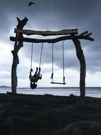 Silhouette man swinging at beach