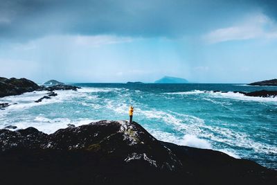 Rear view of man standing on rock at beach