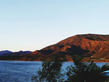 Scenic view of lake and mountains against clear blue sky