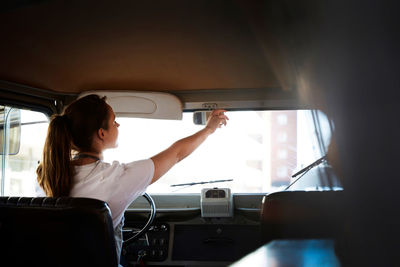 Rear view of female owner adjusting rear-view mirror in food truck