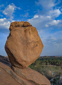 Rock formations on landscape against cloudy sky