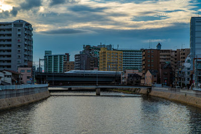 Bridge over river amidst buildings in city against sky