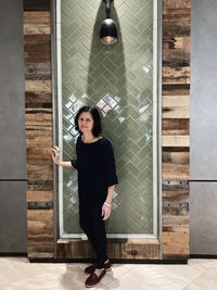 Portrait of woman standing against wall