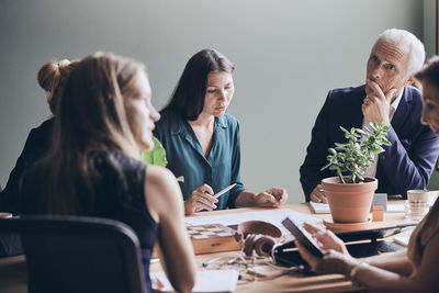 Manager looking at businesswoman planning strategy during meeting in board room