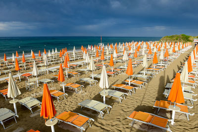 Chairs on beach by sea against sky