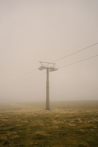 Electricity pylon on field against sky