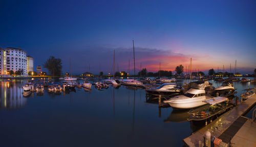 Sailboats moored at harbor against sky during sunset