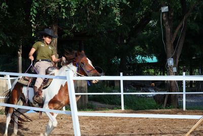 Woman riding horse in ranch