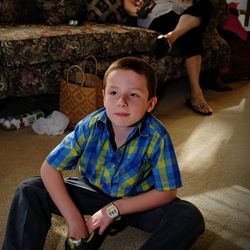 Boy looking away while sitting on rug at home