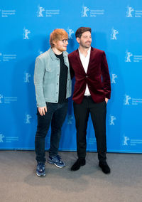 Full length of young man standing against blue wall