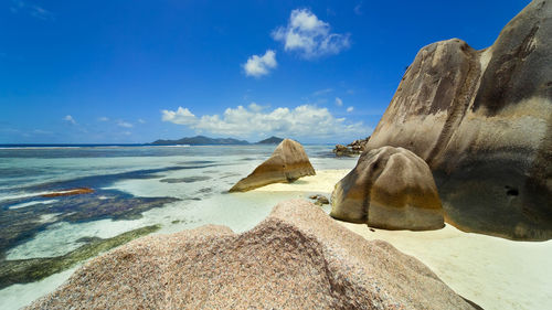 Panoramic view of rocks on beach against blue sky