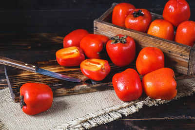 Persimmons with cutting board and burlap on wooden table