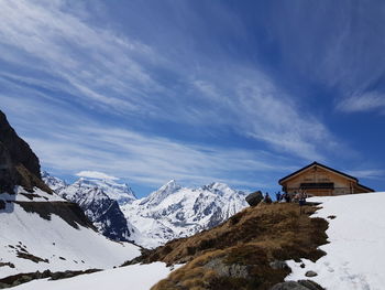 House on snowcapped mountain against sky