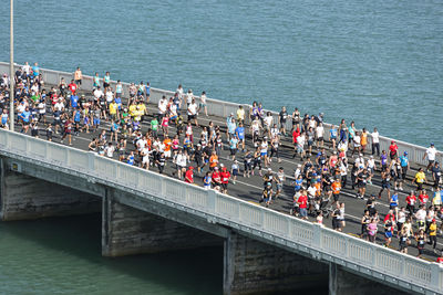 High angle view of people running on bridge over sea