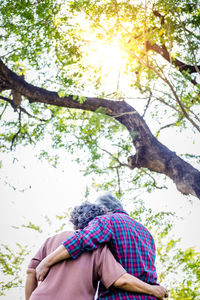 Low angle view of couple sitting on tree