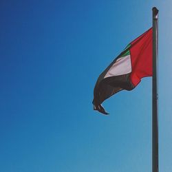 Low angle view of flags against blue sky