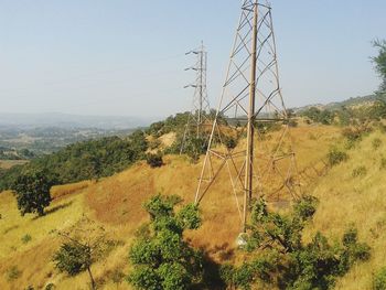 Electricity pylon on landscape against clear sky