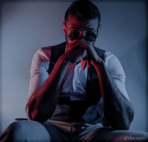 Portrait of young man looking away while sitting against wall