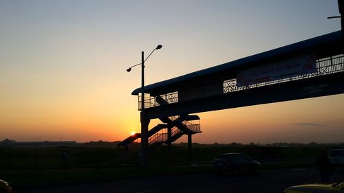 Silhouette bridge against sky during sunset in city