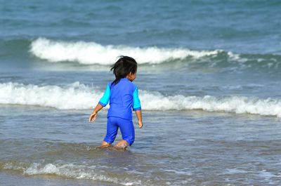 Rear view of boy enjoying at beach