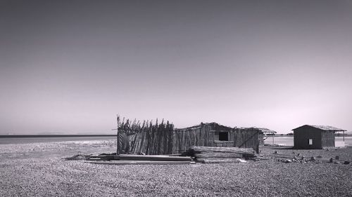 Stilt house on beach against clear sky