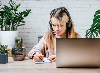 Student girl in headphones watching online video zoom class webinar in virtural classroom on her