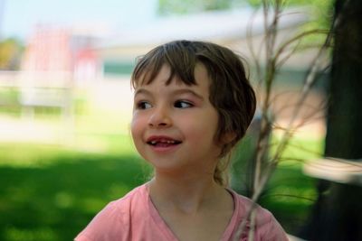 Close-up of thoughtful girl smiling while standing outdoors