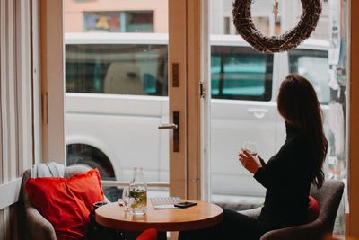 Woman drinking wine while sitting on table in restaurant