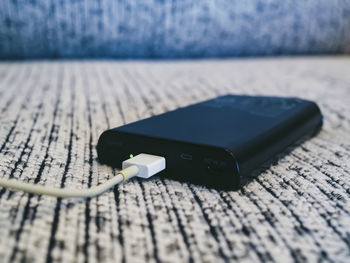Close-up of usb cable connected to portable charger on table