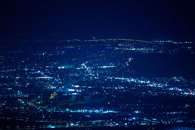 High angle view of illuminated city against sky at night