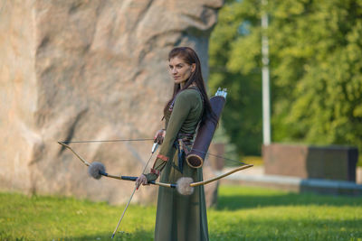 Woman holding umbrella while standing on field