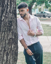 Side view of young man looking through tree trunk