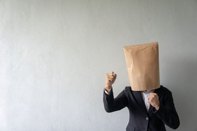 Midsection of a man holding camera against wall