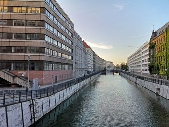 Canal amidst buildings in city against sky