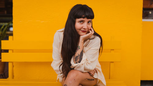 Dark-haired female model in vintage clothing and make-up against a colorful wall.