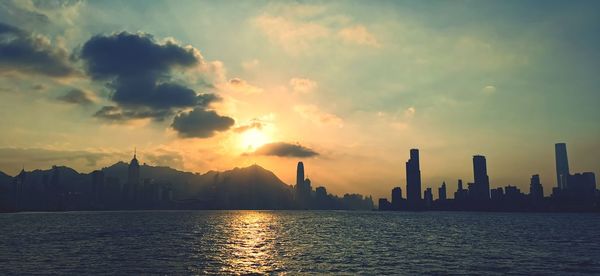 Panoramic view of sea and buildings against sky during sunset