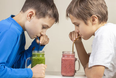 Brothers drinking smoothie on table at home