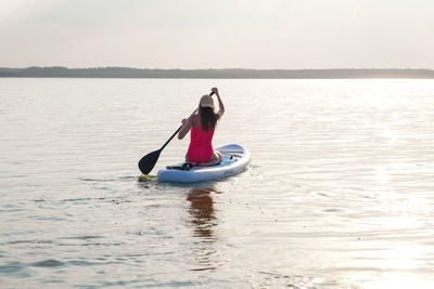 Man kayaking on sea against sky during sunset