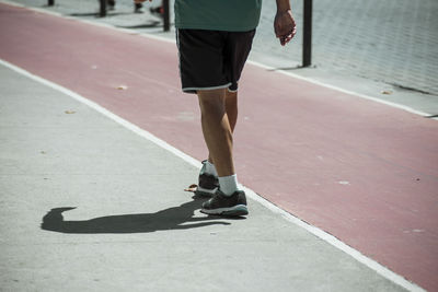 Low section of man walking on road