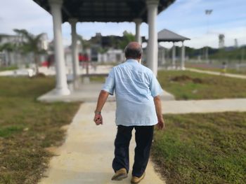 Rear view of man walking on road