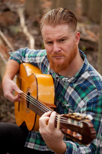Portrait of man playing guitar outdoors