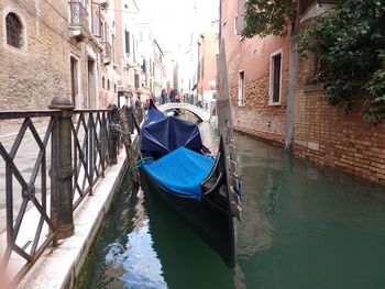 Boats moored in canal amidst buildings