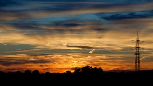 Silhouette landscape against dramatic sky during sunset