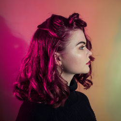 Close-up of beautiful woman by colored background